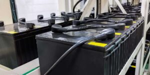 Large black industrial batteries connected in a rack system, demonstrating the setup managed by a UPS battery management system.