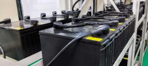 Large industrial UPS battery backup units lined up on metal racks, indicating when system maintenance or replacement is required.