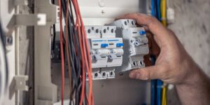 Technician hand adjusting a breaker switch in a panel, highlighting manual maintenance bypass switch controls for UPS system servicing.